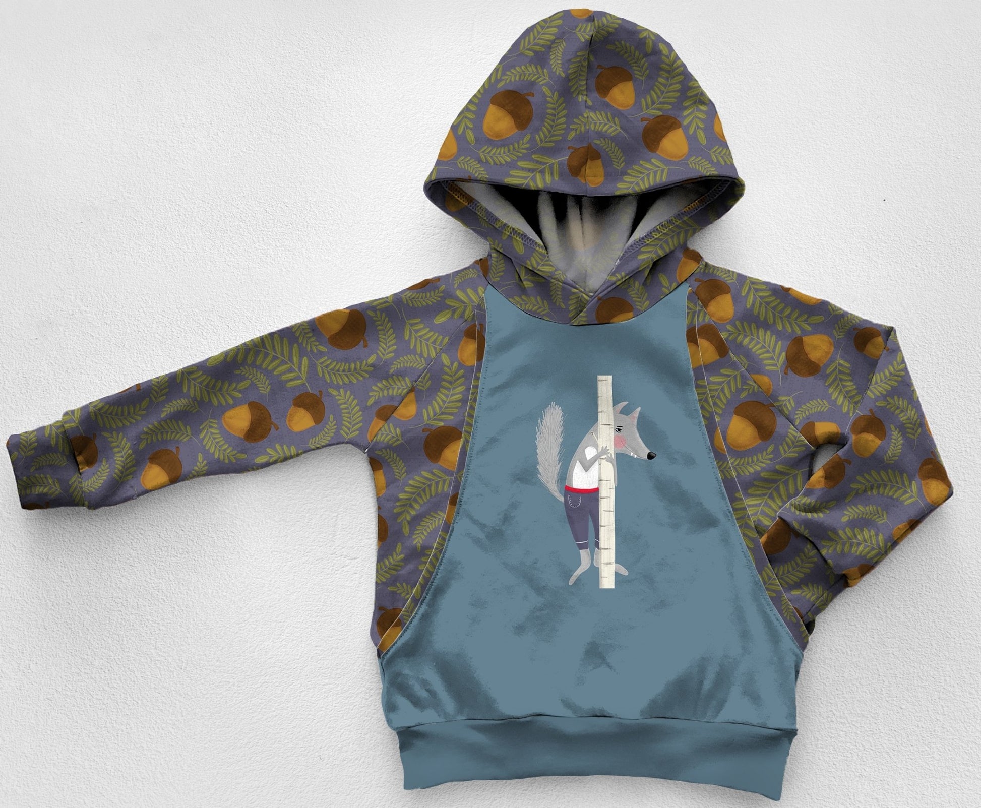 blue hoodie with acorns and a wolf hiding behind a tree