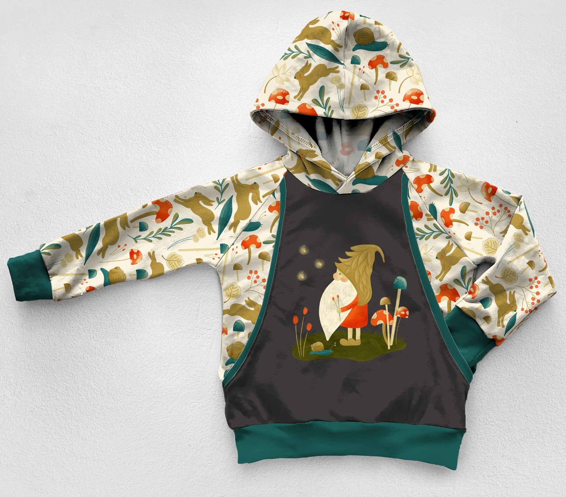 A grey and ivory panel hoodie with a gnome looking at fireflies in the forest