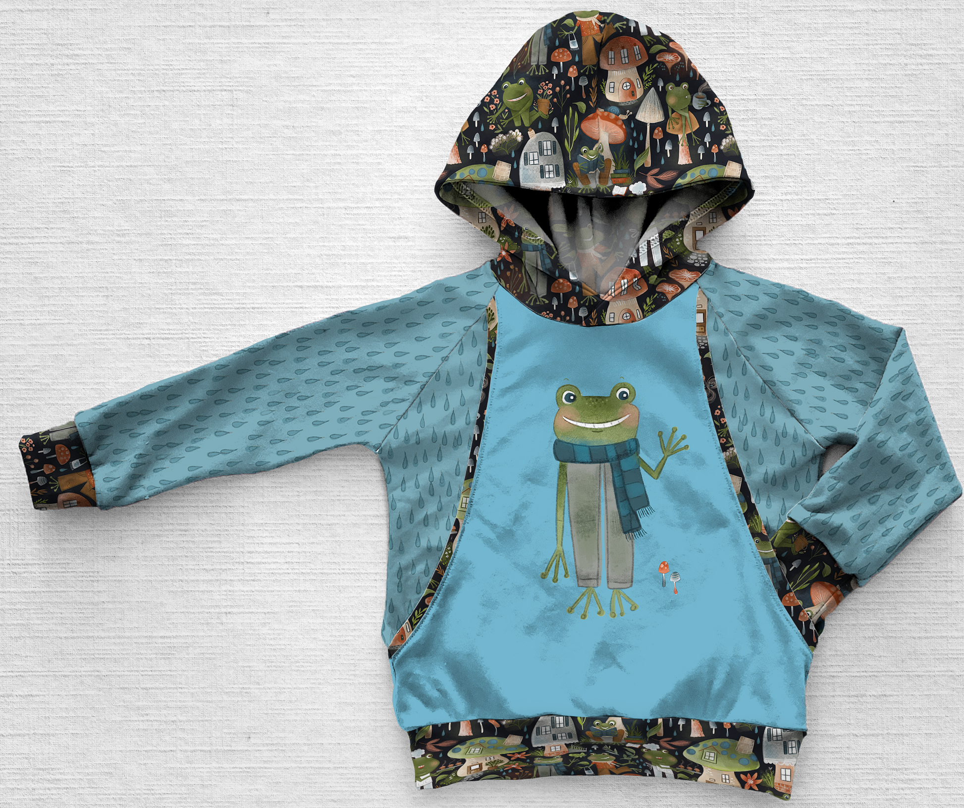 A blue panel hoodie with a frog waving hello and a raindrop print fabric
