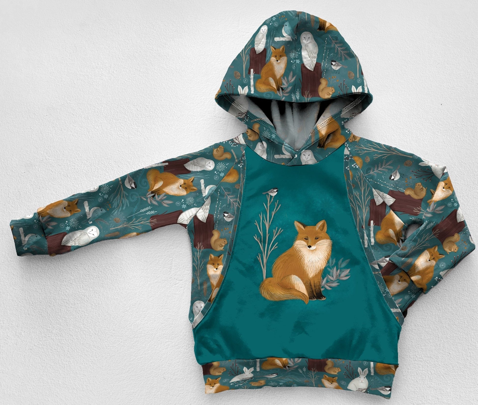 A blue green panel hoodie with a fox, chickadee, squirrel, and owl printed fabric