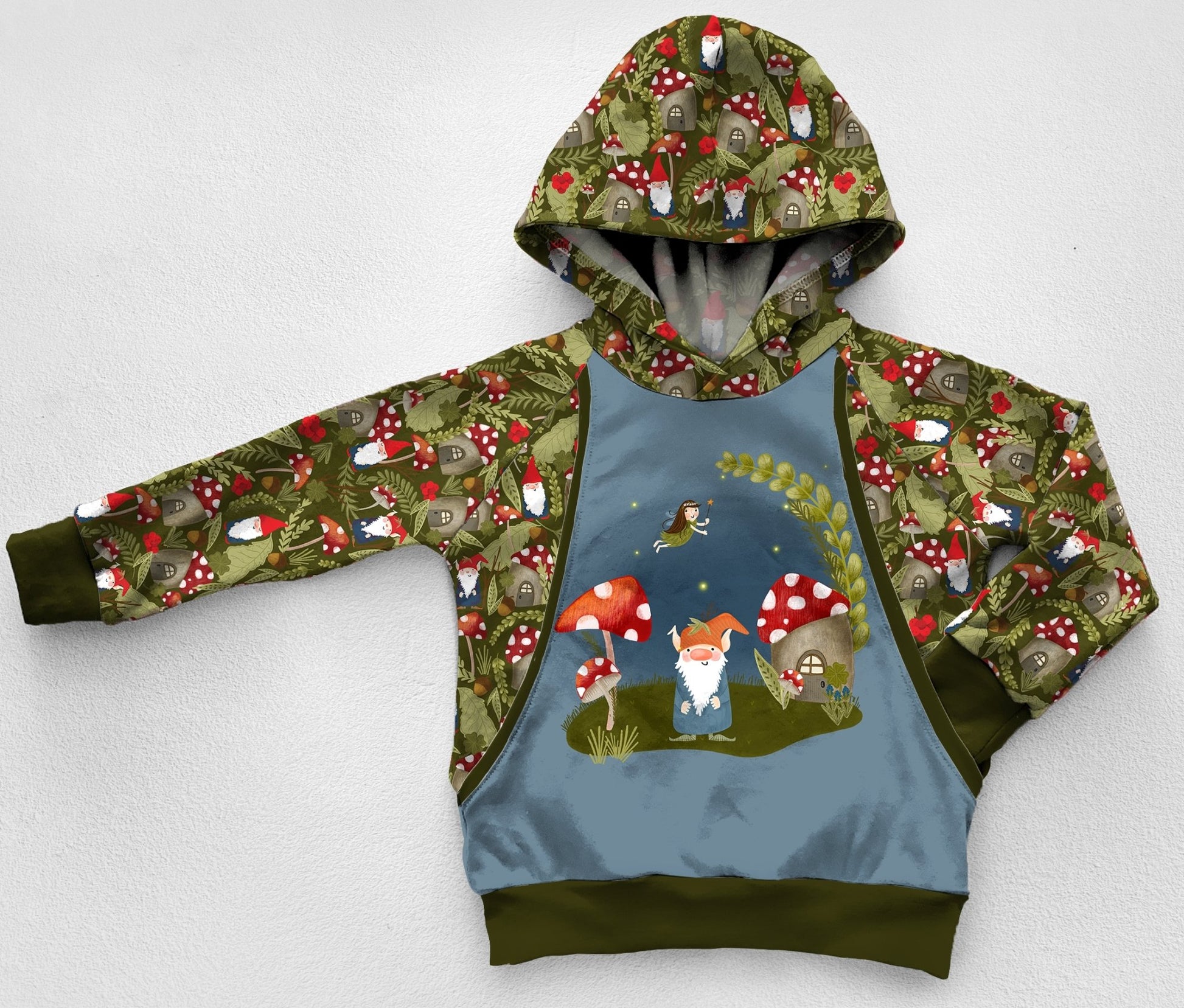 A green and blue panel hoodie with gnomes, forest plants, and red mushrooms. 
